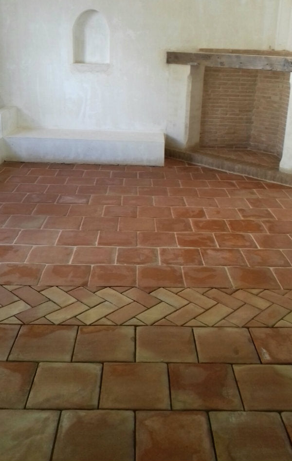 Square and rectangular terracotta floor tiles separated with a patterned row